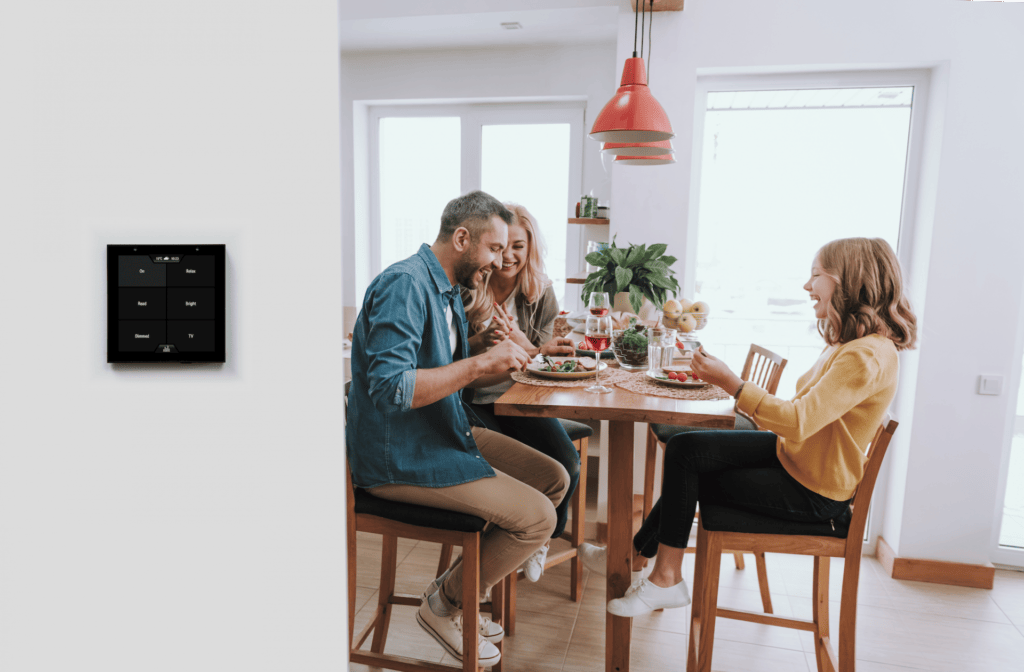 Family having lunch with Violet SmartSwitch Lite showing scenes wall mounted in the foreground