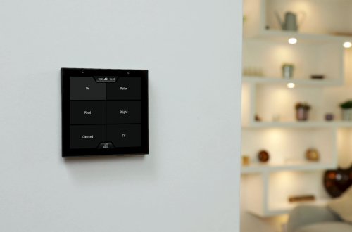 Violet SmartSwitch Lite wall mounted showing scenes screen with illuminated shelves in the background