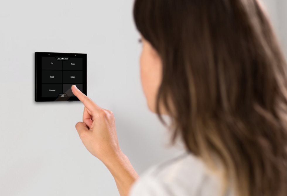 Woman pressing smart light system control button on wall mounted smart home control panel